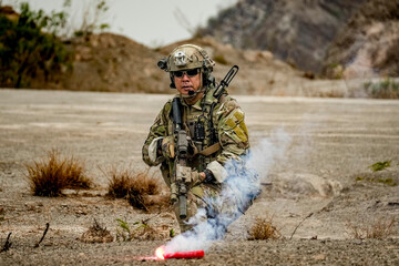 A group of military men in combat gear patrol in the middle of a desert and tropical jungle....