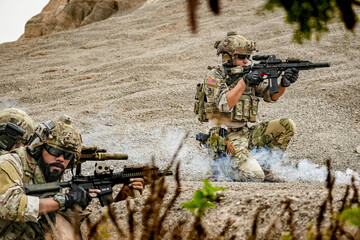 A group of military men in combat gear patrol in the middle of a desert and tropical jungle....