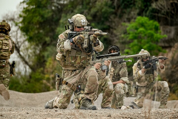 A group of military men in combat gear patrol in the middle of a desert and tropical jungle....