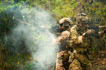 A group of military men in combat gear patrol in the middle of a desert and tropical jungle....