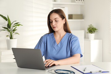 Young nurse working with laptop at desk in hospital