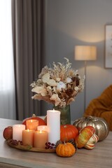 Tray with many burning candles and autumn decor on wooden table indoors