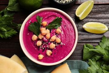 Tasty beetroot hummus in bowl and products on wooden table, flat lay