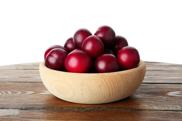 Fresh ripe plums in bowl on wooden table against white background