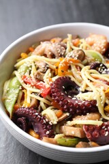 Stir-fry noodles with sea food in bowl on grey table, closeup
