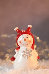 Funny snowman figure on artificial snow against blurred lights