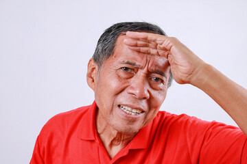 Fototapeta premium Senior asian man hold hand at forehead look far away distance isolated on white background