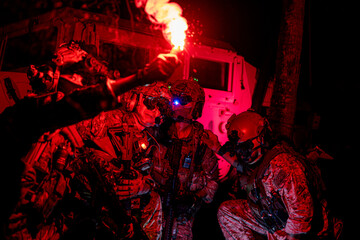 Obraz premium soldiers wearing combat gear gather around a flare during military operation. The dark setting and flare emphasize the stealth and readiness. soldiers using a red flare to strategize night mission.