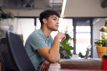 At office, Thinking deeply, man holding pencil and looking away while sitting at desk