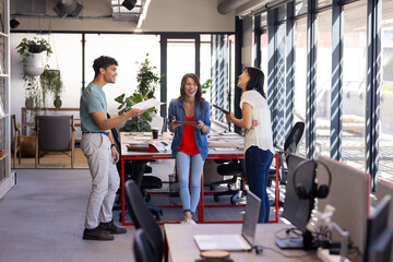 Collaborating in modern office, diverse colleagues discussing design project with tablet