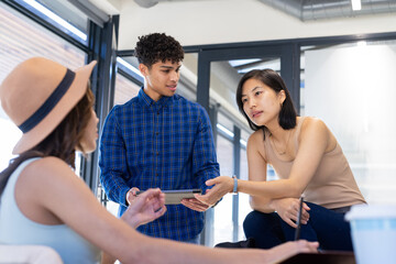 Discussing ideas on interior design project, diverse team collaborating using tablet in office