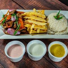 beef lomo saltado, french fries and rice, served with homemade creams, peruvian food