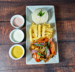 sautéed chicken with french fries and rice, served with homemade creams, peruvian food