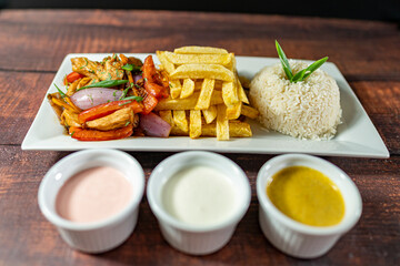 sautéed chicken with french fries and rice, served with homemade creams, peruvian food