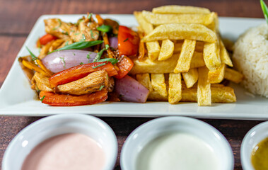 sautéed chicken with french fries and rice, served with homemade creams, peruvian food