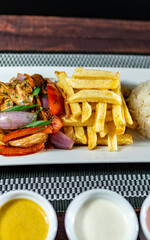 sautéed chicken with french fries and rice, served with homemade creams, peruvian food