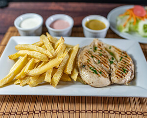 grilled chicken with french fries and fresh salad, accompanied by homemade creams.