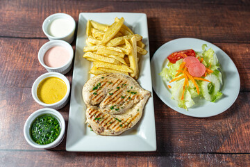 grilled chicken with french fries and fresh salad, accompanied by homemade creams.