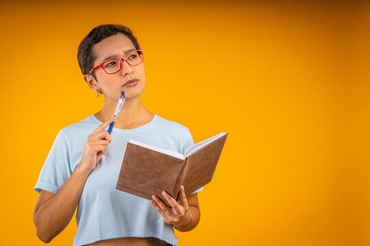 Young woman deep in thought holding pen and notebook