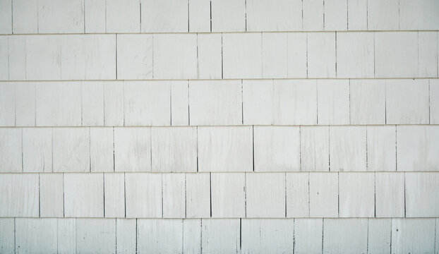 Old building or wall with aged white plain siding of cedar or cement planks or shingles