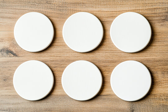 Blank round coasters arranged neatly on rustic wooden table create minimalist aesthetic. These coasters are perfect for protecting surfaces while adding touch of simplicity to any setting