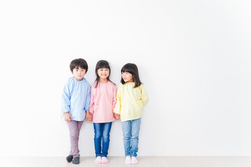 壁に並ぶ3人の幼稚園児