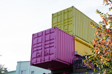 A vibrant pink container along with a striking green shipping container has been carefully stacked on top of one another, creating a unique and intriguing visual feature