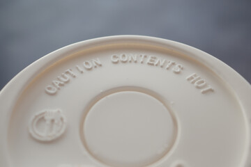 Coffee cup lid with caution hot and recycling symbols for sustainability and safety in urban