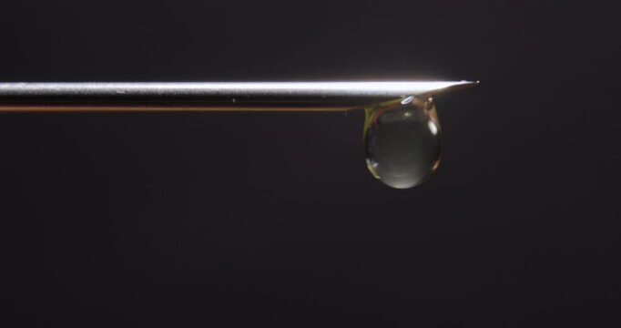 Hypodermic Needle Tip Dripping on Dark Background