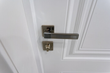 The modern door handle and lock set on a stylish and elegant white door enhances the overall aesthetic and functionality of any home