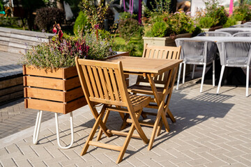 A wooden table and chairs are sitting on a patio next to a wooden planter