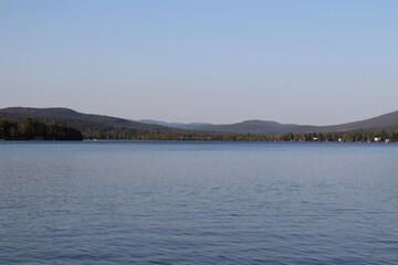 Horizon and lake in summer. Summer background with water and mountain. Environment and ecology. Peaceful image and blue sky.