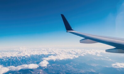 Fototapeta premium Airplane Wing Over Snowy Mountain Range and Clouds