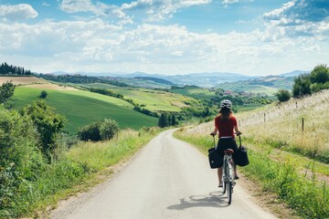 Female tour guide leading a bicycle tour through picturesque countryside. Rolling hills and open fields surround the path
