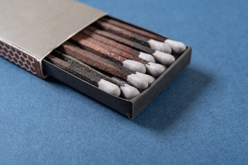 angle view grey color matchbox and grey match sticks on a blue background