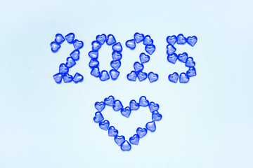 New Year 2025 inscription from glass hearts on a blue background. Pantone color 2025. Idea and creativity. Valentine's Day. Christmas with loved ones. Horizontally, banner. High quality photo