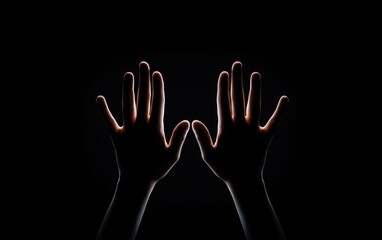 Obraz premium Silhouette of two hands raised against a dark background, symbolizing communication, connection, and expression.