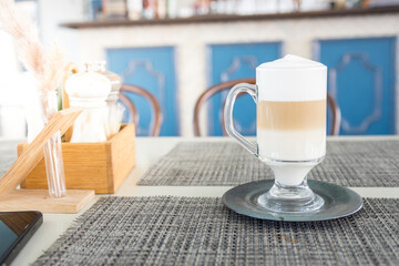 A glass of coffee sits on a table with a wooden box and a vase