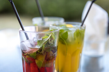 Three drinks with straws in them, one is a pink drink, one is a green drink