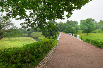 Obraz premium A path in a park with a bridge over a pond