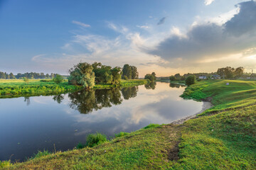 A calm river with a reflection of the sky and trees