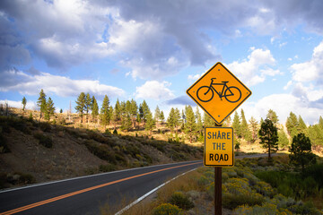 Share the Road Bike Sign on paved road going uphill just before sunset.  Sierra Nevada mountains.