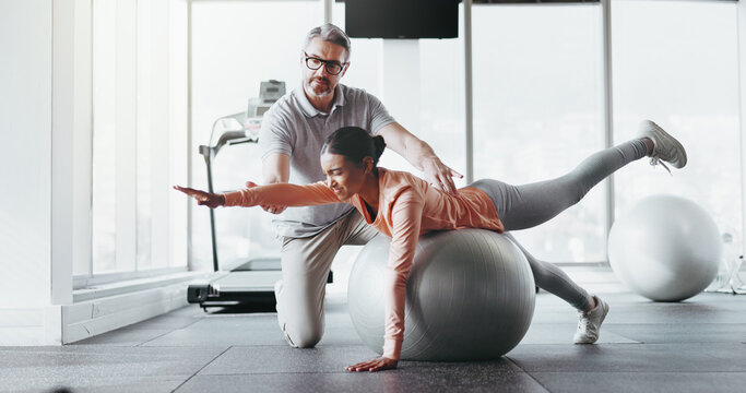 Ball, girl and personal trainer in gym for fitness, rehabilitation or stability training. Man instructor, woman or physiotherapy in yoga center for core strength, pilates practice or help in exercise - Powered by Adobe
