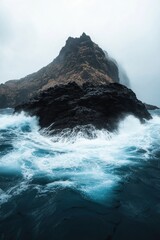 Fototapeta premium A volcanic island emerging from the sea, its dark, jagged rocky surface shrouded in mist and surrounded by rough, crashing waves.
