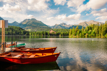 Fototapeta premium Red boats on Mountain lake Strbske pleso. Strbske lake with view of the High Tatras National Park, Slovakia