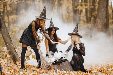 Three witches in forest on Halloween make magic potion