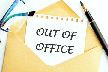 OUT OF OFFICE words written on a white sheet of notepad sticking out of an envelope