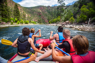 A large group of men and boys on a white water rafting trip down the Colorado River. View from behind of as they seek adventure and fun.