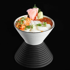 A beautifully presented bowl of Japanese cuisine featuring fresh sashimi ingredients on a black reflective background.