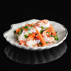 A beautifully presented seafood salad with shrimp and crab sticks on a scallop-shaped white dish, garnished with herbs and vegetables.